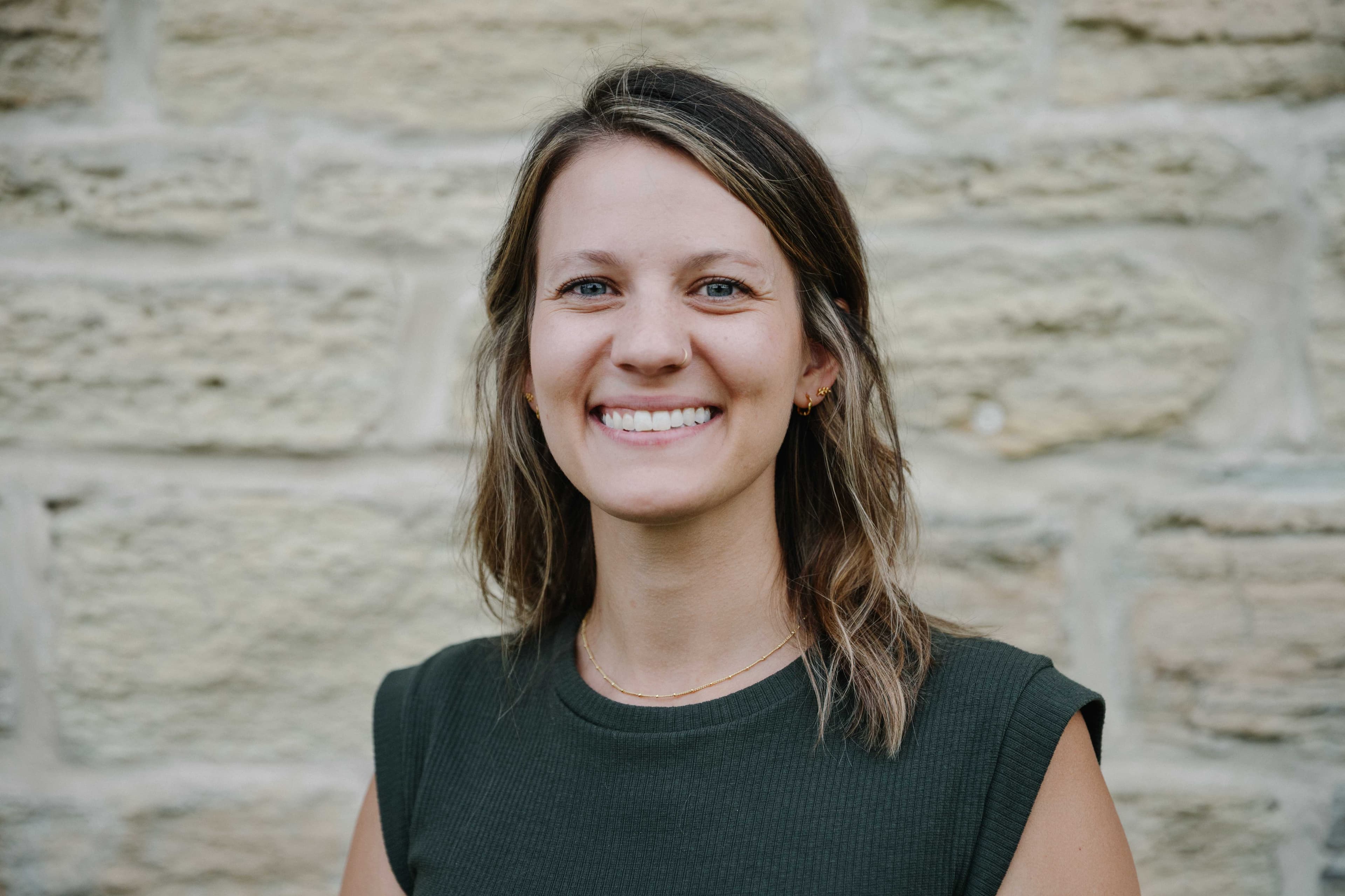Sarah Stetina, MSN, CNM, smiling in front of a limestone wall
